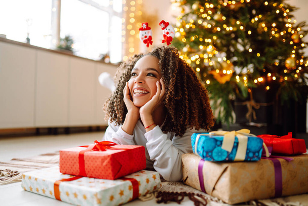 Portrait of happy woman celebrating winter holidays with large gift boxes near Christmas tree. Christmas surprise. - Foto, Imagem