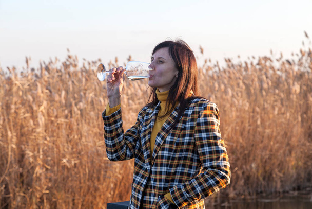 Красивая девушка, деловая женщина, брюнетка в отпуске с бокалом шампанского, на фоне осеннего пейзажа, - Фото, изображение
