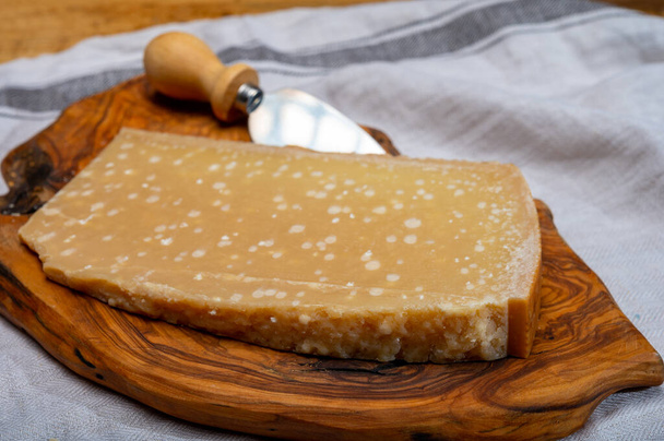 72 months very old Italian parmigiano-reggiano parmesan cheese from Parma has amber color, dry, extremely grainy and crumbly with very intense taste, close up - Photo, Image