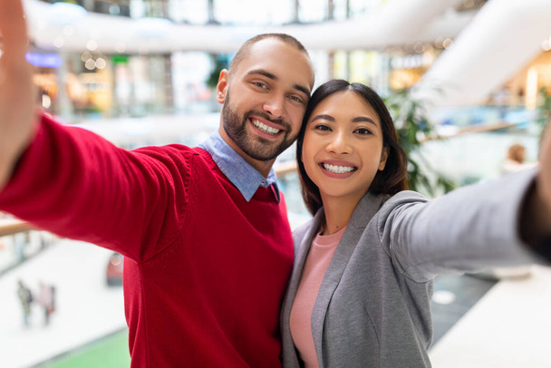 Rakastava nuori monipuolinen pari hymyilee, ottaa selfie valtava ostoskeskus - Valokuva, kuva