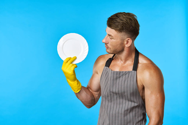 Dishwasher rubber gloves plate in hands blue background - Фото, зображення
