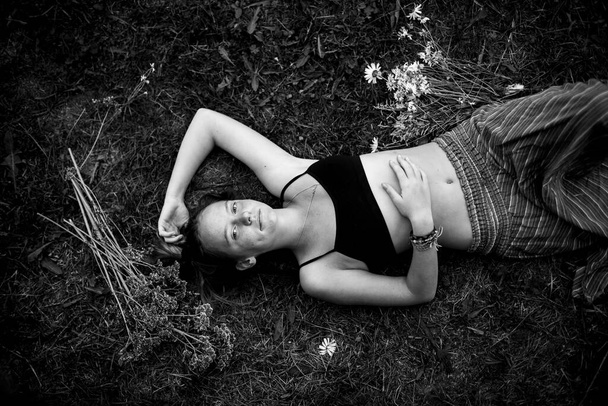 Девушка лежит на траве, застрелена сверху. Черно-белое фото. - Фото, изображение