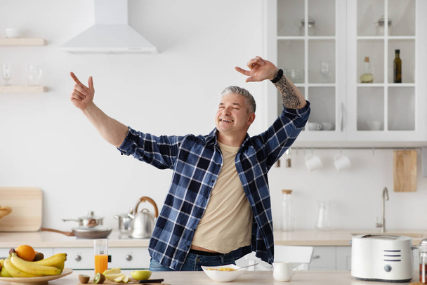 Happy vanhempi mies pelleillä ja tanssia, kun ruoanlaitto aamiainen keittiö sisustus, vapaa tila - Valokuva, kuva