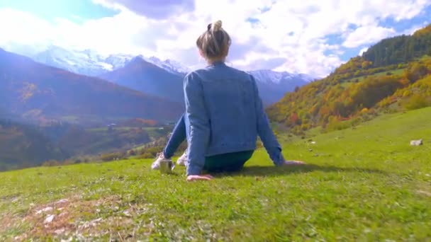 A woman admires the mountains, next to her a metal mug with tea or coffee. - Footage, Video