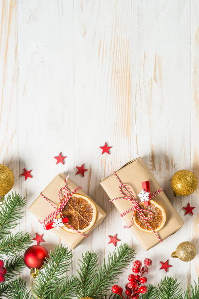 Weihnachtshintergrund mit Tanne, Geschenkbox und Dekoration am weißen Holztisch. - Foto, Bild