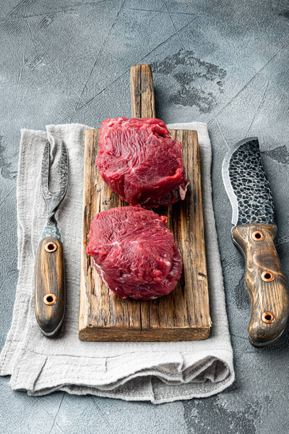 Biftecks de sanglier au filet cru frais bœuf marbré au romarin et à l'ail, sur planche à découper en bois, sur fond de pierre grise - Photo, image