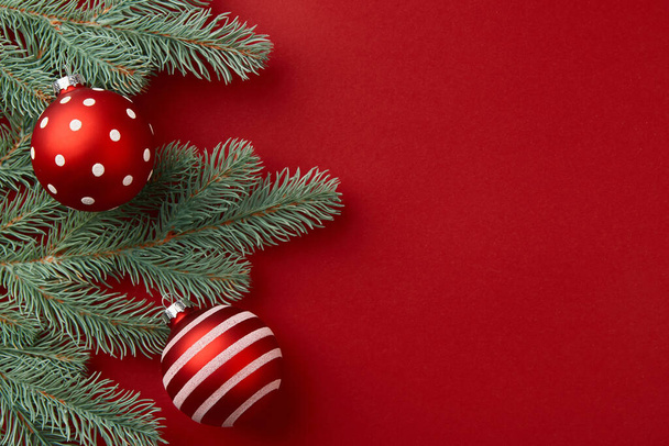 Karácsonyi kompozíció. Karácsonyfa ágak és díszek piros háttér - Fotó, kép
