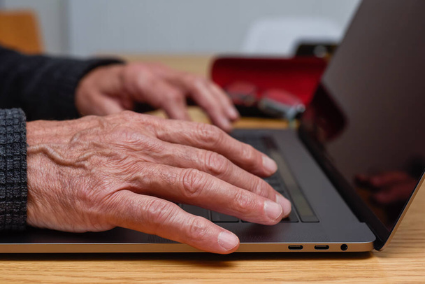 老人ホームでラップトップを使用してキーボード上の手で詳細をクローズアップ - 写真・画像