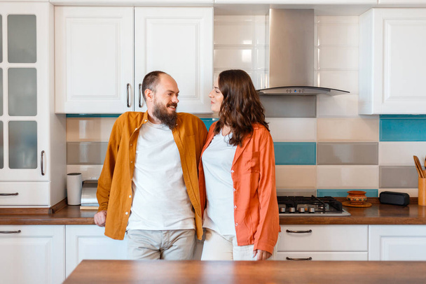 Happy young couple talking at home in kitchen. Family Husband and wife enjoying spending time together while standing in apartment interior. Love in Good relationship - Fotoğraf, Görsel