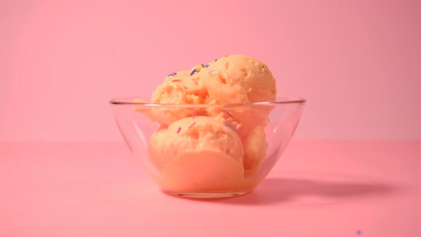 Mangová zmrzlina ve skleněné misce. Skořápka mangové zmrzliny posypaná barevným cukrem. Zmrzlina se sypkou - Záběry, video
