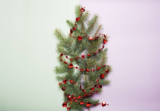 Christmas concept, green pine tree branches with little red hearts decor on a light green and lilac background. Empty space for text. - Fotografie, Obrázek