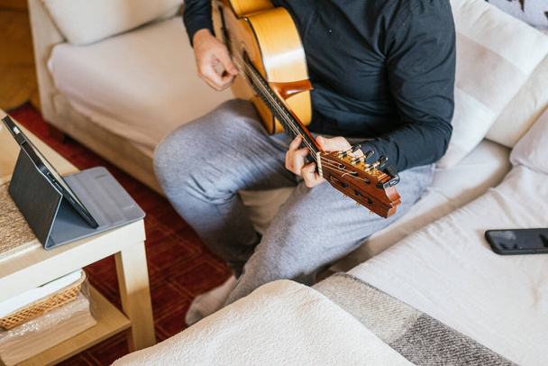 Человек берет уроки игры на гитаре дома. - Фото, изображение