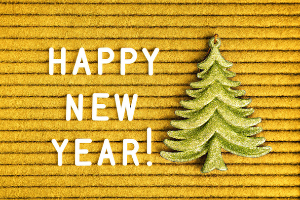 Szczęśliwego Nowego Roku, tekst na żółtym filcu tablicy z białymi literami i zielonej jodły zabawki - Zdjęcie, obraz