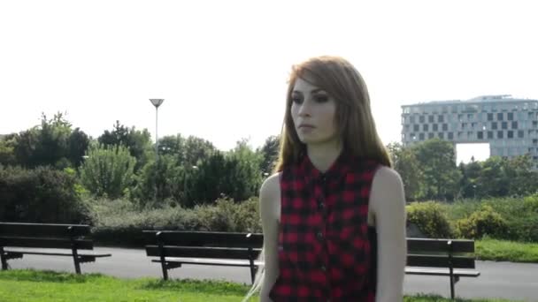 Молода приваблива жінка йде в парк природа з сучасними будівлями на задньому плані
 - Кадри, відео