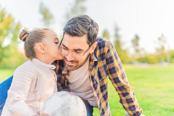 słodkie mała dziewczyna całuje jej samotny ojciec w parku - Zdjęcie, obraz
