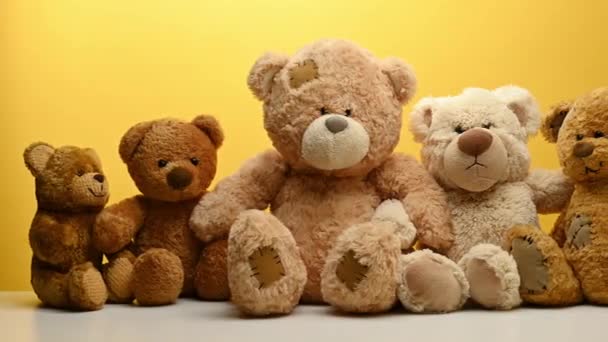 group of cute brown teddy bears sit on yellow background, childrens toy - Footage, Video