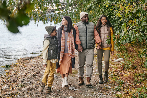 szczęśliwy młody międzyrasowy rodzina z czterech korzystających spacer na jesienny dzień - Zdjęcie, obraz