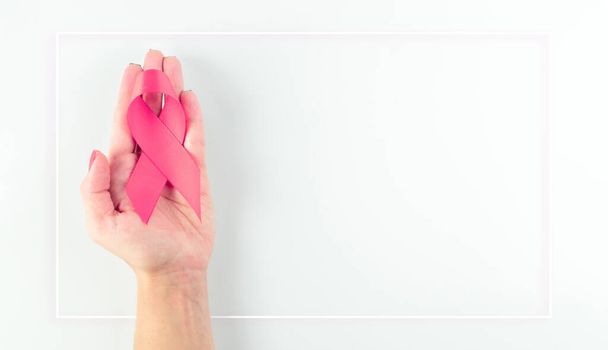 癌の背景。女性の手は白い背景に健康管理のシンボルピンクのリボンを保持。コピースペースと乳癌のサポート - 写真・画像