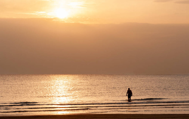 Silueta muže v moři při východu slunce. Neznámá osoba, která ráno vplouvá do oceánu na koupání. - Fotografie, Obrázek