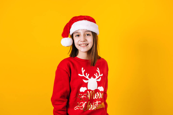 Portrait of latin child girl with christmas hat on a yellow background in Mexico latin america - 写真・画像