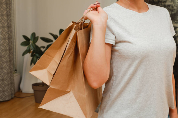 Ecological packaging. The girl holds paper bags in her hands. Happy cute unrecognizable woman came home from shopping with eco-friendly recycled paper bags. - Фото, зображення