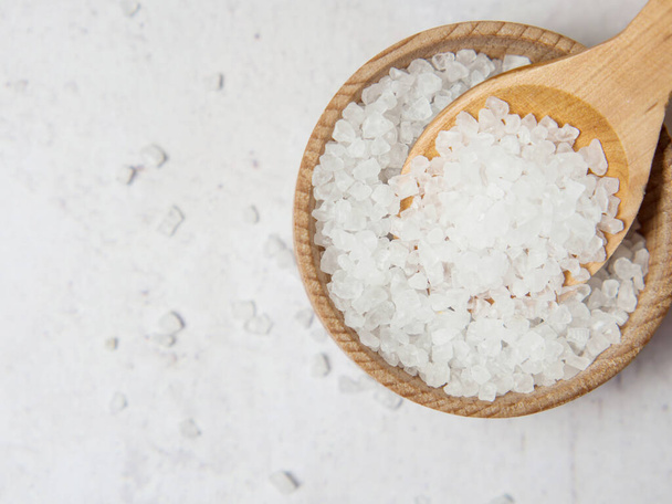 Большая белая морская соль в деревянной ложке на бетонном фоне вблизи - Фото, изображение