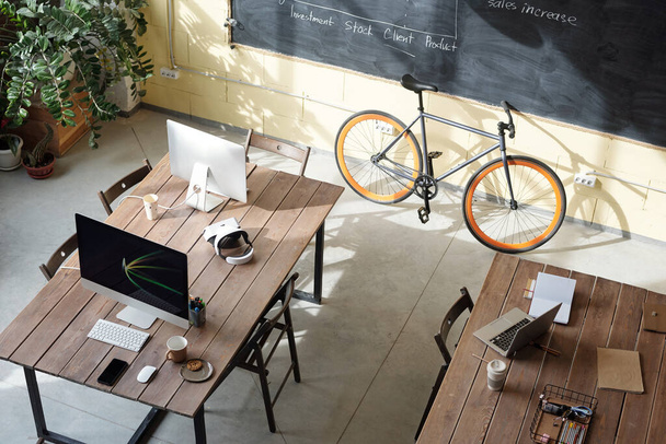 Два столи з комп'ютерами, ноутбуком і велосипедом на дошці
 - Фото, зображення