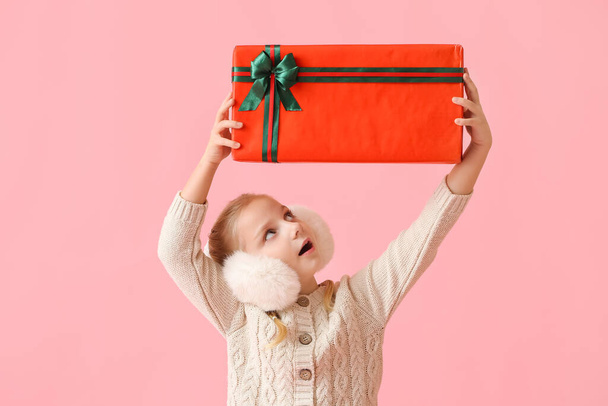 Überrascht Mädchen mit Weihnachtsgeschenk auf farbigem Hintergrund - Foto, Bild