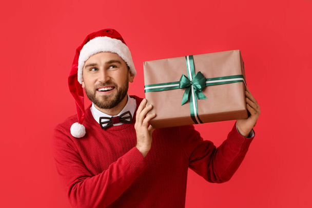 Szczęśliwy młody człowiek z prezentem świątecznym na tle koloru - Zdjęcie, obraz