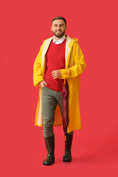 Young man in stylish raincoat and with umbrella on color background - Photo, image