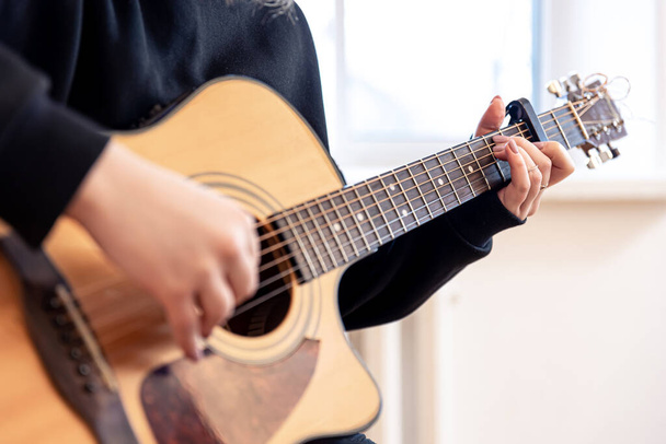 Une femme joue de la guitare acoustique, gros plan. - Photo, image