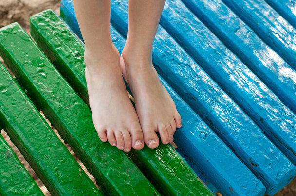 bare children's feet are standing on a beach bench - Photo, Image