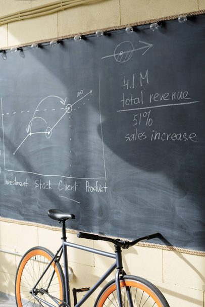 Dane ekonomiczne i wykresy na tablicy i rowerze pracownika biurowego - Zdjęcie, obraz