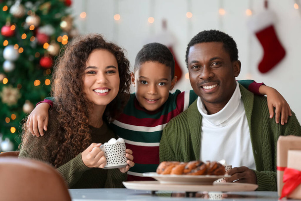 Glückliche afroamerikanische Familie trinkt an Heiligabend zu Hause leckere heiße Schokolade - Foto, Bild