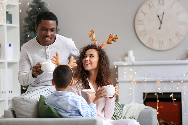 Glückliche afroamerikanische Familie trinkt an Heiligabend zu Hause leckere heiße Schokolade - Foto, Bild