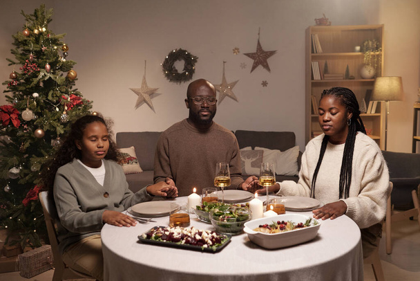 Християнська сім'я з трьох осіб молилася перед святковою вечерею. - Фото, зображення