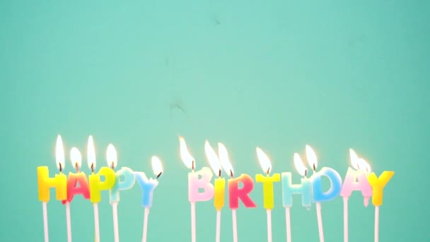 Happy Birthday concept Made of Burning Colorful Candles on blue or turquoise background. Blowing out the Happy birthday candles. Slow motion full HD video - Footage, Video