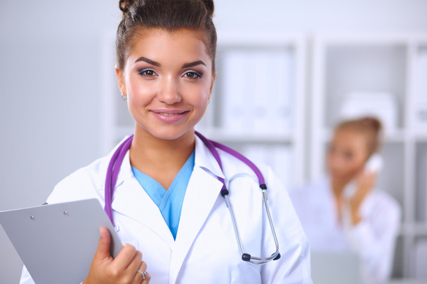 Smiling female doctor with a folder in uniform standing at hosp - Фото, изображение