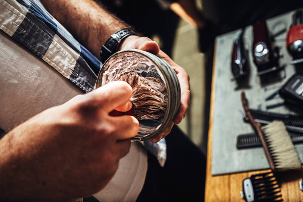 Barber in the barbershop preparing shaving foam in a bowl with a brush. - Foto, Imagem