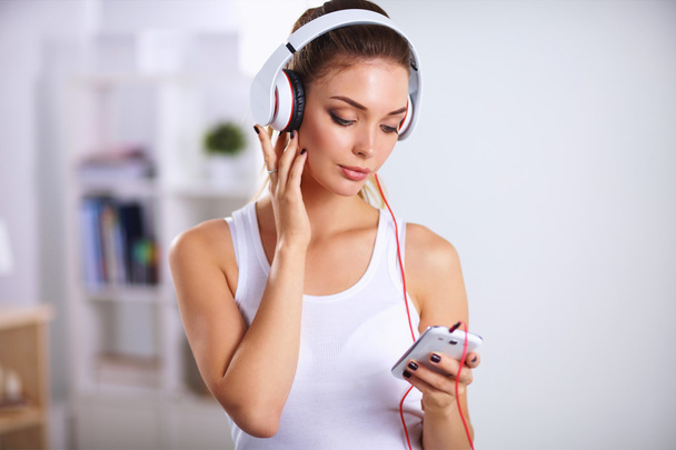 Woman with headphone listening music standing at home - Valokuva, kuva