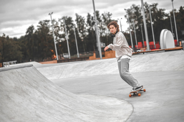 Girl with outstretched hand on skateboard riding in skatepark - Foto, Imagen