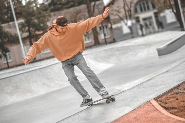 Guy with hands to sides riding skateboard in skatepark - Fotó, kép