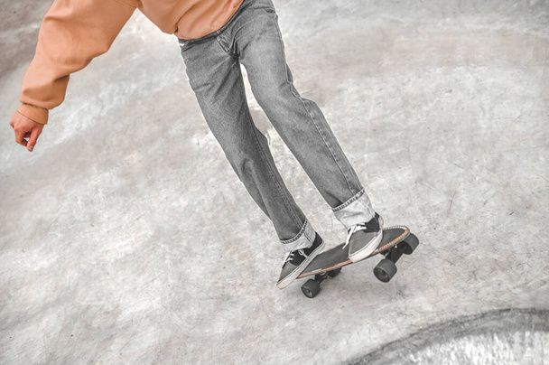 Beine von Kerl rutschen auf Skateboard auf glatter Oberfläche - Foto, Bild