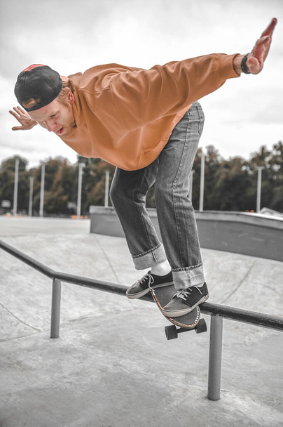 Guy on skateboard flying over railing in skatepark - Фото, изображение