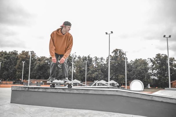 Guy on skateboard crouched down sliding on bollard - Foto, imagen