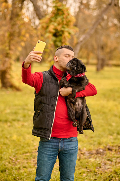 A man with his dog in hands making selfie - Foto, imagen
