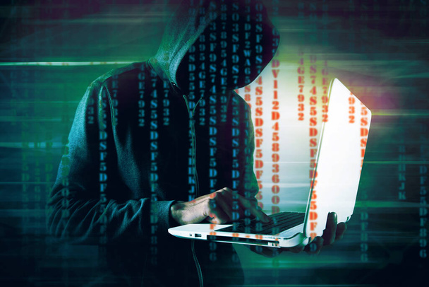 hacker in the hood holds a laptop - 写真・画像