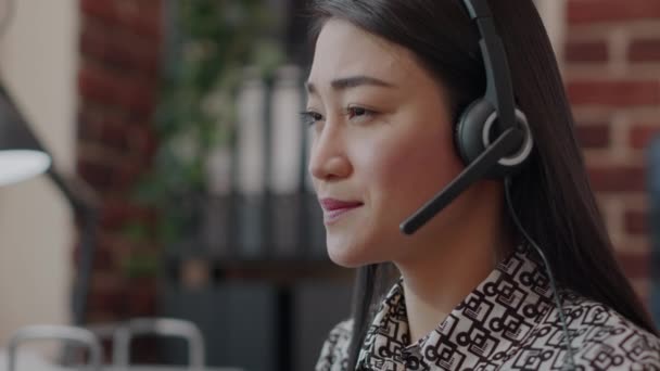 Zbliżenie pracownika call center ze słuchawkami rozmawiającymi przez telefon - Materiał filmowy, wideo