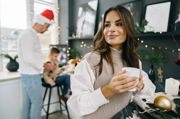 Attractive young woman drinks tea in the kitchen for Christmas - Фото, зображення