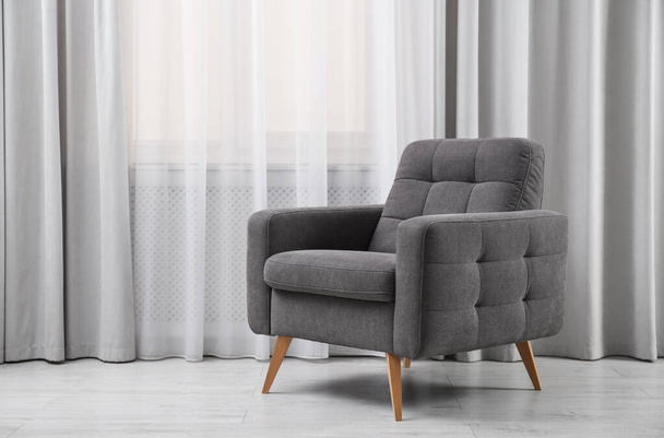 Comfortable armchair near window with stylish curtains in living room. Interior design - Fotó, kép